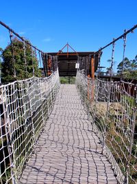 Footpath by footbridge against sky