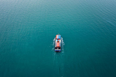 Aerial top view container ship sailing on the green sea full speed container for logistics, import 