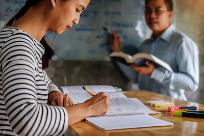 Midsection of couple holding book on table