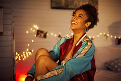 Young woman looking away while sitting in illuminated room