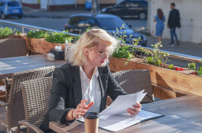 Woman holding ice cream while sitting on table