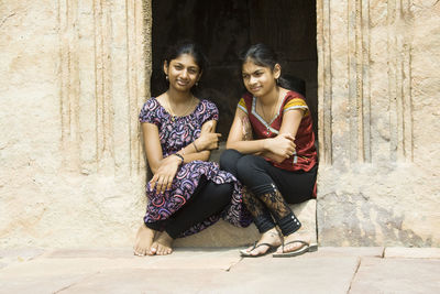 Full length of smiling young woman sitting outdoors