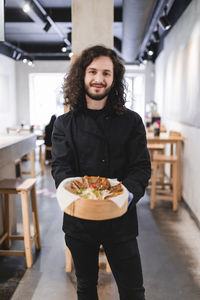 Portrait of male chef with dumplings in bowl standing at restaurant