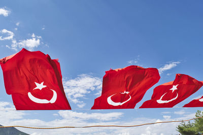 Low angle view of red turkish flag against blue sky