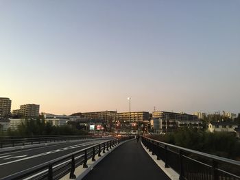 Road passing through city against sky during sunset