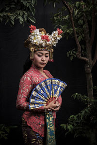 Portrait of woman in traditional clothing standing against flowering plants