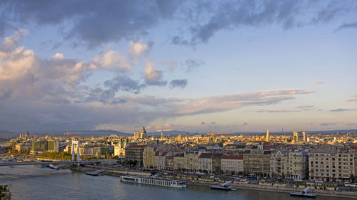 River amidst buildings in city against sky during sunset