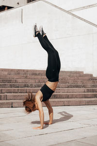 Strength woman doing handstand in the city. urban background .