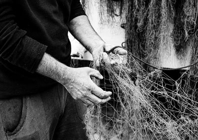 Midsection of man holding tangled fishing net