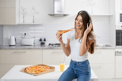 Smiling young woman holding ice cream at home