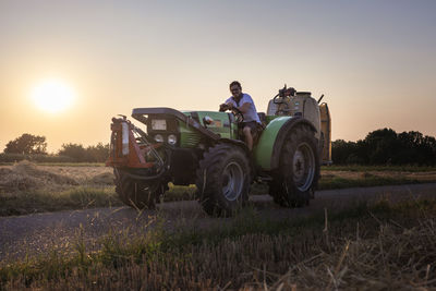 Organic farmer on a tractor at sunset