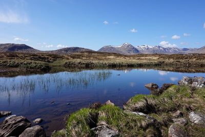 Scenic view of lake and mountains against blue sky