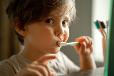 The boy brushes his teeth with a toothbrush made of ecological material