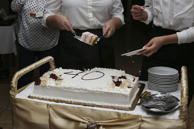 Close-up of hands holding cake on table