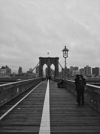 Rear view of people walking on footbridge in city