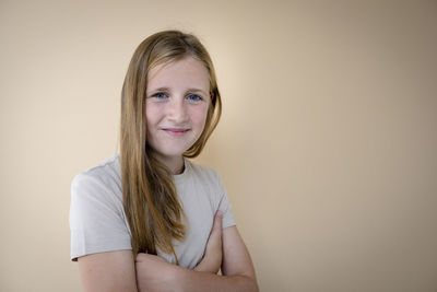 Portrait of young woman standing against wall