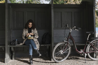 Woman with bicycle having lunch break on station platform, berlin, germany