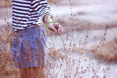 Midsection of woman holding plant on field