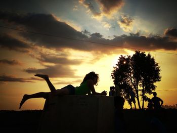 Low angle view of silhouette man sitting against orange sky