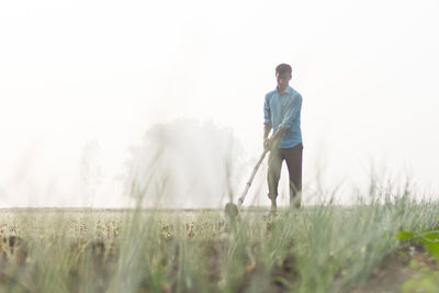 Man standing on golf course against sky