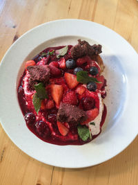 High angle view of forest fruits in sauce with brownie bits in plate on table