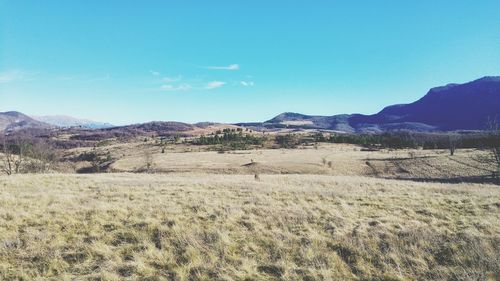 Scenic view of landscape and mountains against blue sky