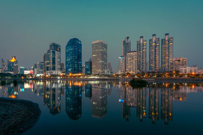 Reflection of illuminated buildings in river against sky