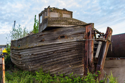 Abandoned boat on land against sky