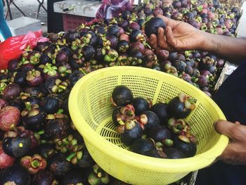 Man picking mangosteens from stall