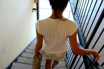 Rear view of woman moving down on staircase in building