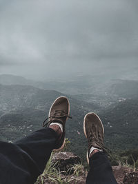 Low section of people on mountain against sky