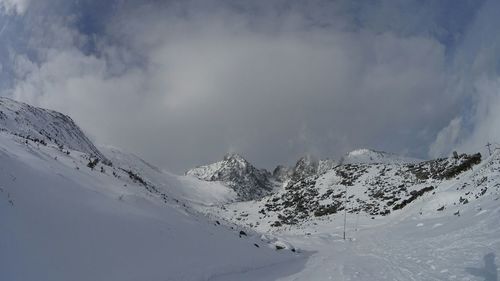 Snow covered mountains against cloudy sky