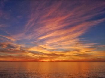 Scenic view of sea against dramatic sky during sunset