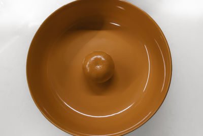 Mandarin in orange colored circular bowl, minimal still life