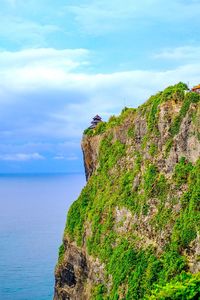 Scenic view of rocks by sea against sky