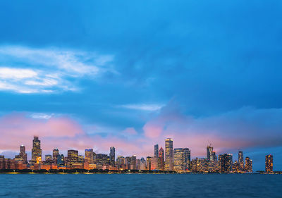 Sea by buildings against blue sky in city