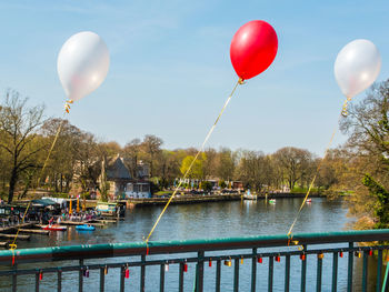 Hot air balloon flying over lake against sky