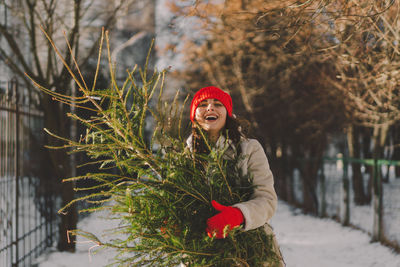 A beautiful girl in a red hat carries a christmas tree. christmas tree