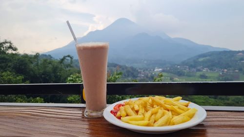 Close-up of drink on table against mountains