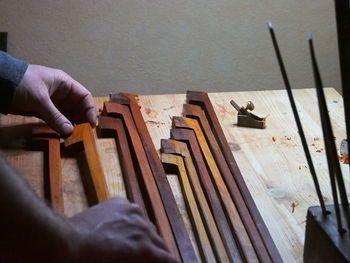 Cropped hands of carpenter holding wood at table in workshop