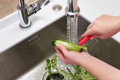 Midsection of woman with faucet in water at home