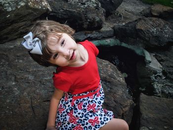 High angle view of cute girl sitting on rock in park