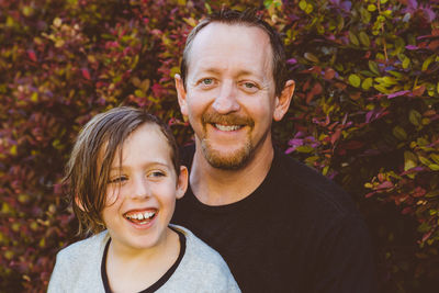 Portrait of smiling father and son against plants