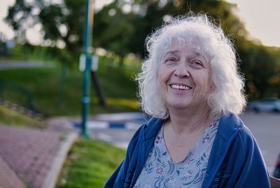 Attractive grey-haired curly senior woman smiling while looking at the camera. copy space.