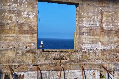 Old building by sea against blue sky