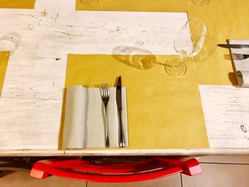High angle view of wineglass with cutlery on wooden table