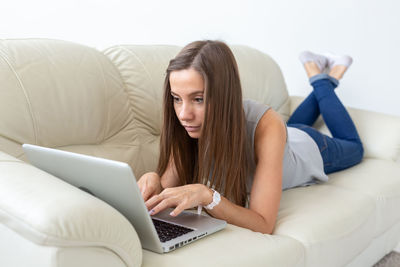 Young woman using mobile phone while sitting on sofa