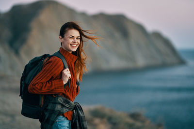 Portrait of smiling young woman standing against sea