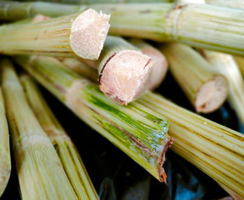 A pile of sugarcane stalks on a table selling sugarcane juice on the side of the road.