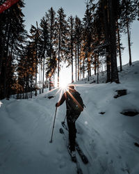 Rear view of woman skiing on snow covered landscape